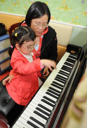 Song Xinyi (L) learns how to play piano from Huang Yanlin, a professor of Sichuan Conservatory of Music, in Chengdu, capital city of southwest China's Sichuan Province, on October 27, 2009. 