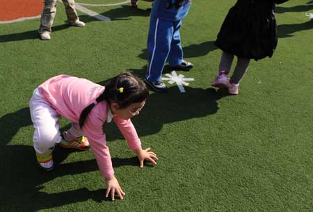 Song Xinyi helps herself up after falling down on the ground in her kindergarten in Chengdu, capital city of southwest China's Sichuan Province, on October 27, 2009.
