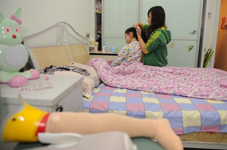 Song Xinyi (L) sits on her bed as the girl friend of her uncle undoes her hair in Chengdu, capital city of southwest China's Sichuan Province, on October 27, 2009. 