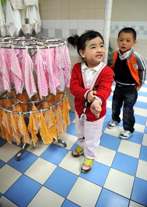 Song Xinyi (L) smiles in her kindergarten in Chengdu, capital city of southwest China's Sichuan Province, on October 26, 2009. 