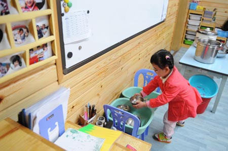 Song Xinyi puts back the dishes in her kindergarten in Chengdu, capital city of southwest China's Sichuan Province, on October 26, 2009. 