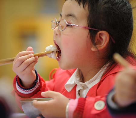 Song Xinyi enjoys her meal in her kindergarten in Chengdu, capital city of southwest China's Sichuan Province, on October 26, 2009.