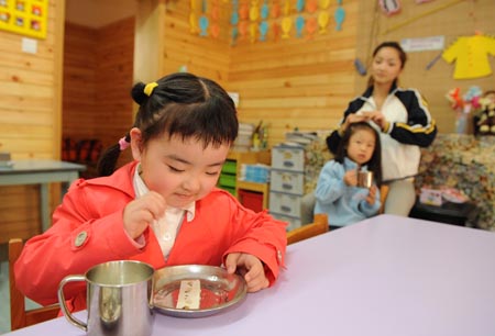 Song Xinyi (L) enjoys a piece of cake in her kindergarten in Chengdu, capital city of southwest China's Sichuan Province, on October 27, 2009.