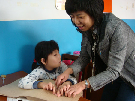 Photo taken by Zhao Congrui shows that Jiao Yao (L), a visually-impaired girl, teaches a lady how to read Braille in Tianjin School for the Visually Impaired in Tianjin, north China, October 28, 2009.