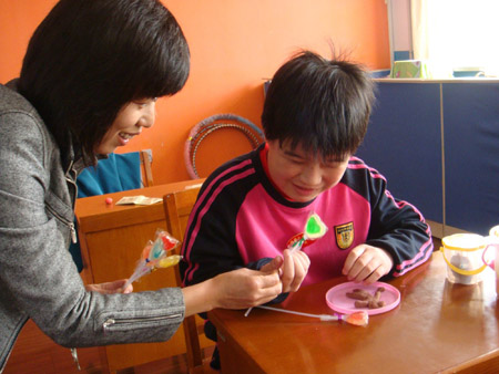 Photo taken by Zhao Congrui shows that Huo Dongran (R), a visually-impaired girl, receives lollipops in Tianjin School for the Visually Impaired in Tianjin, north China, October 28, 2009.