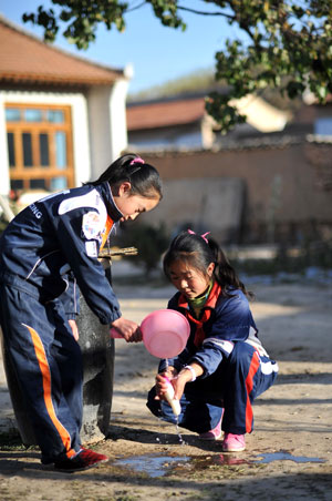 Hai Qin (R), a 12-year-old girl of Hui ethnic group, washes a radish with her sister Hai Ling after school, in Kaicheng Town of Guyuan City, northwest China&apos;s Ningxia Hui Autonomous Region, Oct. 22, 2009.