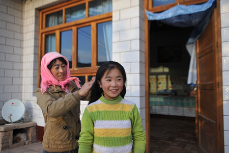 Hai Qin, a 12-year-old girl of Hui ethnic group, is combed her hair by her mother Ma Haihua in Kaicheng Town of Guyuan City, northwest China&apos;s Ningxia Hui Autonomous Region, Oct. 23, 2009.