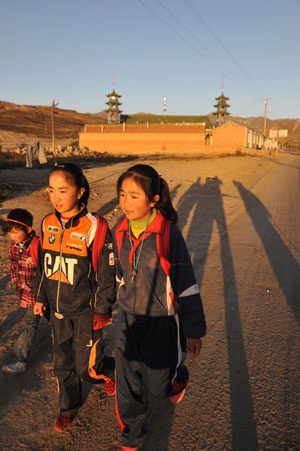 Hai Qin (R), a 12-year-old girl of Hui ethnic group, walks with her little sister Hai Ling en route to school, in Kaicheng Town of Guyuan City, northwest China&apos;s Ningxia Hui Autonomous Region, Oct. 23, 2009.