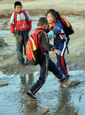 Hai Qin, a 12-year-old girl of Hui ethnic group, reaches out hand to help a classmate crossing a brook en route to school, in Kaicheng Town of Guyuan City, northwest China&apos;s Ningxia Hui Autonomous Region, Oct. 23, 2009.