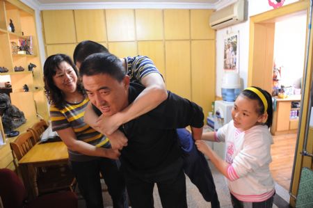 Liu Mengyi (R) helps parents get her brother for bath room at their home in Qingdao, east China's Shandong Province, October 15, 2009.