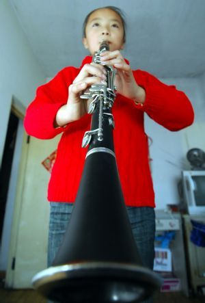 Liang Yuxin plays clarinet which is rent with 200RMB by her grandfather in Harbin, capital of northeast China's Heilongjiang Province, October 21, 2009. 