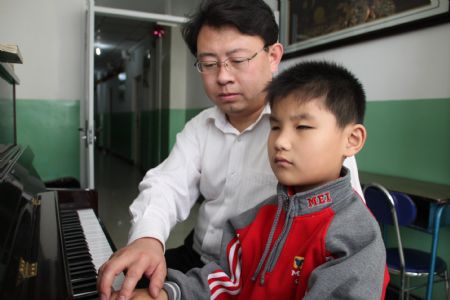 Liu Hao, an eight-year-old blind boy of a worker's family, learns playing piano with his teacher Liu Yongxue, in Chifeng City, north China's Inner Mongolia Autonomous Region, November 3, 2009.