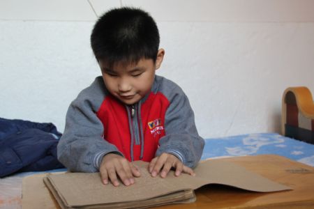 Liu Hao, an eight-year-old blind boy of a worker's family, learns the Braille by himself at home, in Chifeng City, north China's Inner Mongolia Autonomous Region, November 3, 2009.