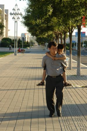 Liu Hao, an eight-year-old blind boy of a worker's family, is carried on the back of his piano teacher Liu Yongxue en route to piano room for practice, in Chifeng City, north China's Inner Mongolia Autonomous Region, July 9, 2009.