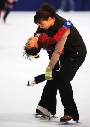 Zhang Mingyang (L) skates with her teacher's help during evening exercises in Harbin, capital of northeast China's Heilongjiang Province, October 30, 2009. 