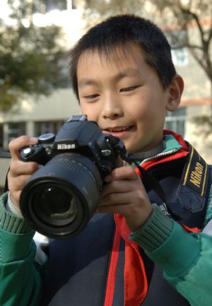 Chen Ming, a grade 5 pupil, reviews the photos he has just taken, on camera view frame, in Xining, capital of northwest China's Qianghai Province, October 30, 2009. 