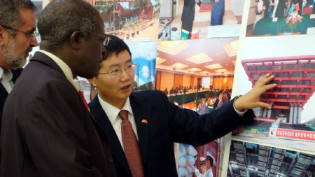 Xu Jianguo (1st R), Charge d'Affairs of China's embassy to Uganda, briefs the exhibited photos to Gaggawala Wambuzi (2nd R), Uganda's minister of state for trade, at a photo exhibition at the Chinese Embassy in Kampala, capital of Uganda, November 9, 2009. The photo exhibition opened here on Monday, in a move to showcase the achievements of follow up actions of the Beijing Summit of the Forum on Sino-Africa Cooperation. 