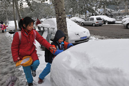 Two pupils play with snow in Beijing, capital of China, November 10, 2009. Beijing witnessed the second snowfall this winter on November 10. 