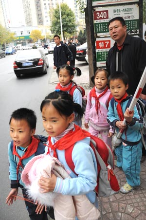 Quintuplets children of Jiao Baocun and his wife Wang Cuiying wait for the bus with their father in Beijing on October 30, 2009.