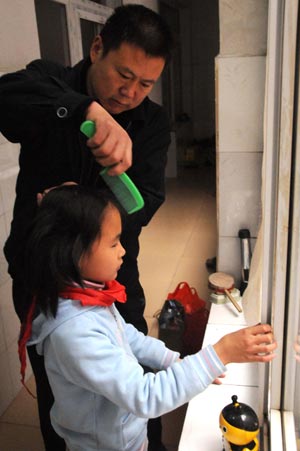 Jiao Baocun combs the hair for Fuli, the third child of quintuplets children of Jiao Baocun and his wife Wang Cuiying, at their home in Beijing on October 30, 2009.