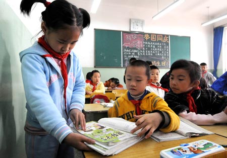 Fuqing, the group leader in her class and the eldest child of quintuplets children of Jiao Baocun and his wife Wang Cuiying, collects the exercise notebooks of her classmates at Experimental Primary School of Fengtai District in Beijing on October 29, 2009.