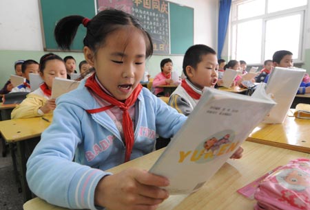 Fuqing (Front), the eldset child of quintuplets children of Jiao Baocun and his wife Wang Cuiying, reads textbook in her class at Experimental Primary School of Fengtai District in Beijing on October 29, 2009.