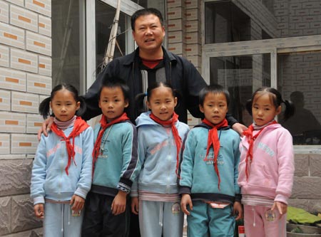 Quintuplets children of Jiao Baocun and his wife Wang Cuiying take photo together with their father at their home in Fengtai District in Beijing on October 30, 2009.