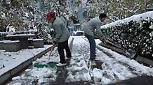 People clean up snow on a road in the Yicuiyuan community in Beijing, capital of China, November 10, 2009. Beijing witnessed the second snowfall this winter on November 10.