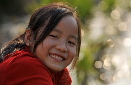 Gao Yaqian, an 8-year-old pupil of the Central Primary School of Lirang Town, smiles while enjoying a leisure moment at home, in Liangping County, southwest China's Chongqing municipality, November 4, 2009.