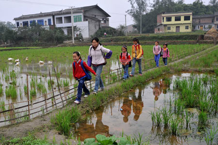 Gao Yaqian (Front), an 8-year-old pupil of the Central Primary School of Lirang Town, goes back home with schoolmates, in Liangping County, southwest China's Chongqing municipality, October 30, 2009.