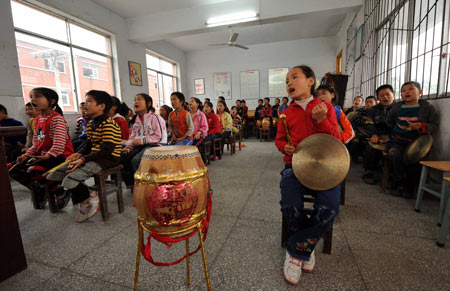 Gao Yaqian, an 8-year-old pupil of the Central Primary School of Lirang Town, learns to play gong and drum, in Liangping County, southwest China's Chongqing municipality, October 30, 2009. 