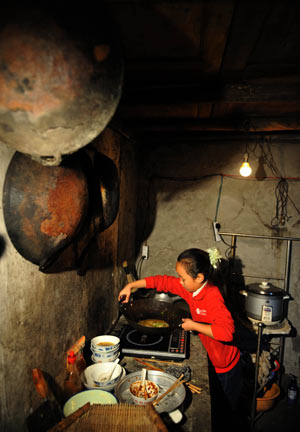 Gao Yaqian, an 8-year-old pupil of the Central Primary School of Lirang Town, prepares meal at home, in Liangping County, southwest China's Chongqing municipality, October 30, 2009.