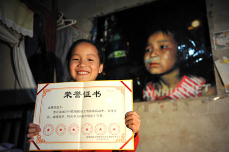 Gao Yaqian, an 8-year-old pupil of the Central Primary School of Lirang Town, shows her certificate of merit with a smiling face for new life at home in Liangping County, southwest China's Chongqing municipality, October 30, 2009.