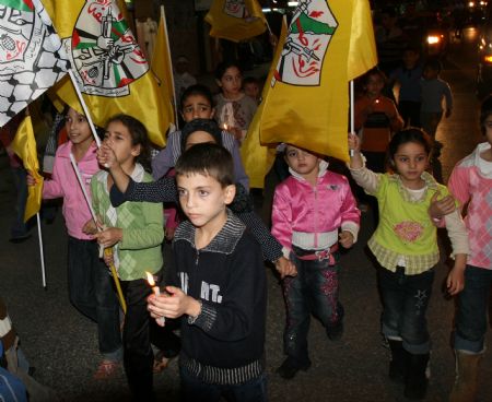 Palestinian kids hold flags and candles during a candle-lighting ceremony marking the fifth anniversary of late Palestinian leader Yasser Arafat's death in the West Bank town Qalqilya, November 10, 2009. Yasser Arafat passed away in Paris on November 11, 2004.