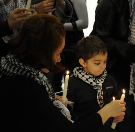 A Palestinian woman helps her son light candles at the grave of the late Palestinian leader Yasser Arafat during a vigil marking the fifth anniversary of Arafat's death in the West Bank city of Ramallah, November 10, 2009.