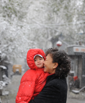 A woman holding a child walks in snow in Beijing, capital of China, November 12, 2009. Snowfall continued in most parts of north and central China on Thursday.