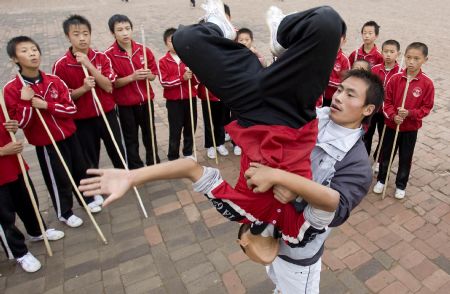 He Minxian, a 9-year-old kid, practises somersault, assisted by his coach, in the Shaolin Tagou Kung Fu (Martial Art) Institute at the foot of Mountain Song in Dengfeng, a city of central China's Henan Province, October 12, 2009. 