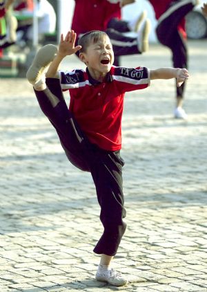 He Minxian, a 9-year-old kid, practise basic skills during a team training class in the Shaolin Tagou Kung Fu (Martial Art) Institute at the foot of Mountain Song in Dengfeng, a city of central China's Henan Province, October 12, 2009.