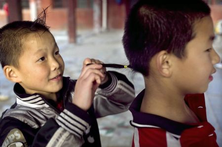 He Minxian (L), a 9-year-old kid, makes a braid for a classmate in the Shaolin Tagou Kung Fu (Martial Art) Institute at the foot of Mountain Song in Dengfeng, a city of central China's Henan Province, October 12, 2009.