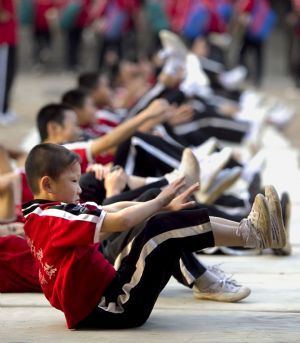 He Minxian (Front), a 9-year-old kid, and his classmates practise to enhance strength in the Shaolin Tagou Kung Fu (Martial Art) Institute at the foot of Mountain Song in Dengfeng, a city of central China's Henan Province, October 12, 2009. 