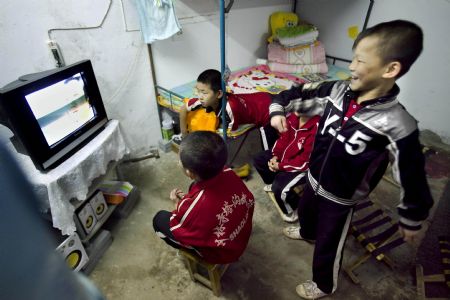 He Minxian (R), a 9-year-old kid, and his classmates watch TV in their dormitary of the Shaolin Tagou Kung Fu (Martial Art) Institute at the foot of Mountain Song in Dengfeng, a city of central China's Henan Province, October 12, 2009.