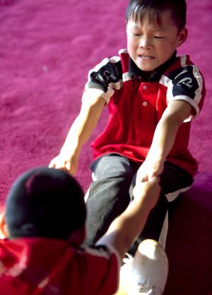 He Minxian (Top), a 9-year-old kid, and his classmates stretch themselves in the Shaolin Tagou Kung Fu (Martial Art) Institute at the foot of Mountain Song in Dengfeng, a city of central China's Henan Province, October 12, 2009.