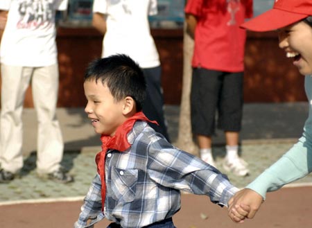 Assisted by a volunteer, Chen Yu (L), a 7-year-old blind boy, runs in the 100 meter competiton at a sports games in the Nanchang Blind Children's School in Nanchang, capital city of east China's Jiangxi Province, on October 30, 2009.