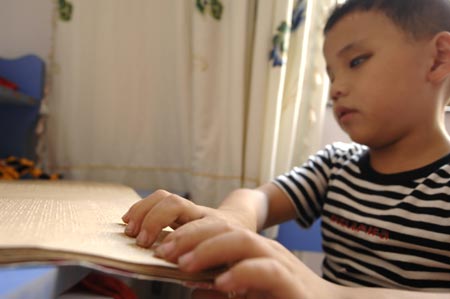 Chen Yu, a 7-year-old blind boy, reviews lessons with a braille book at home in Nanchang, capital city of east China's Jiangxi Province, on October 31, 2009.