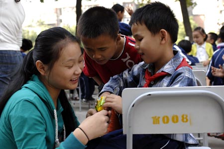 Chen Yu (R), a 7-year-old blind boy, shares his snacks with his classmates during the school sports games of the Nanchang Blind Children's School in Nanchang, capital city of east China's Jiangxi Province, on October 30, 2009. 