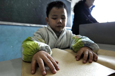 Chen Yu, a 7-year-old blind boy, reads braille in the classroom of the Nanchang Blind Children's School in Nanchang, capital city of east China's Jiangxi Province, on November 4, 2009. 