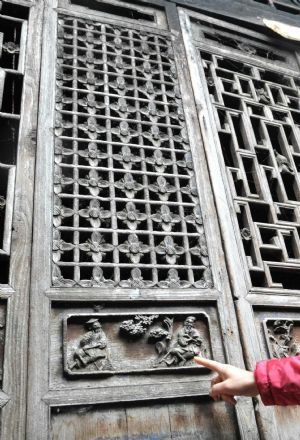 Photo taken on November 15, 2009 shows a visitor points at a carved wooden door of the Ming Dynasty at Fuxi Village with lots of ancient architectures that date to the Ming and Qing Dynasties in Fuchuan Yao Autonomous County, southwest China's Guangxi Zhuang Autonomous Region. 