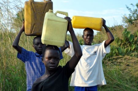 Denis Opoka (1st R) and his brother and sister carry water home at Ajulu village, in Gulu district, northern Uganda, on October 20, 2009. 