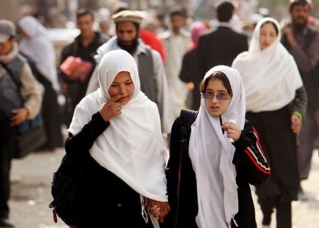 Aysha (R) walks with a classmate through a market for school in Kabul, capital of Afghanistan, on November 1, 2009.