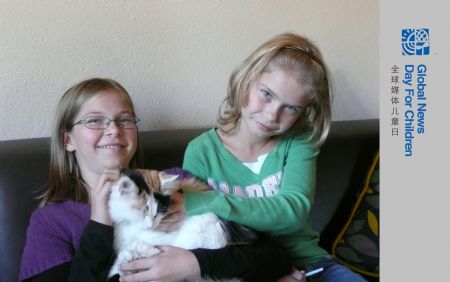 Flora (L) and Valentina pose for a photo with their pet kitty at their home in Purkersdorf, a town of Lower Austria, Austria, on October 18, 2009.